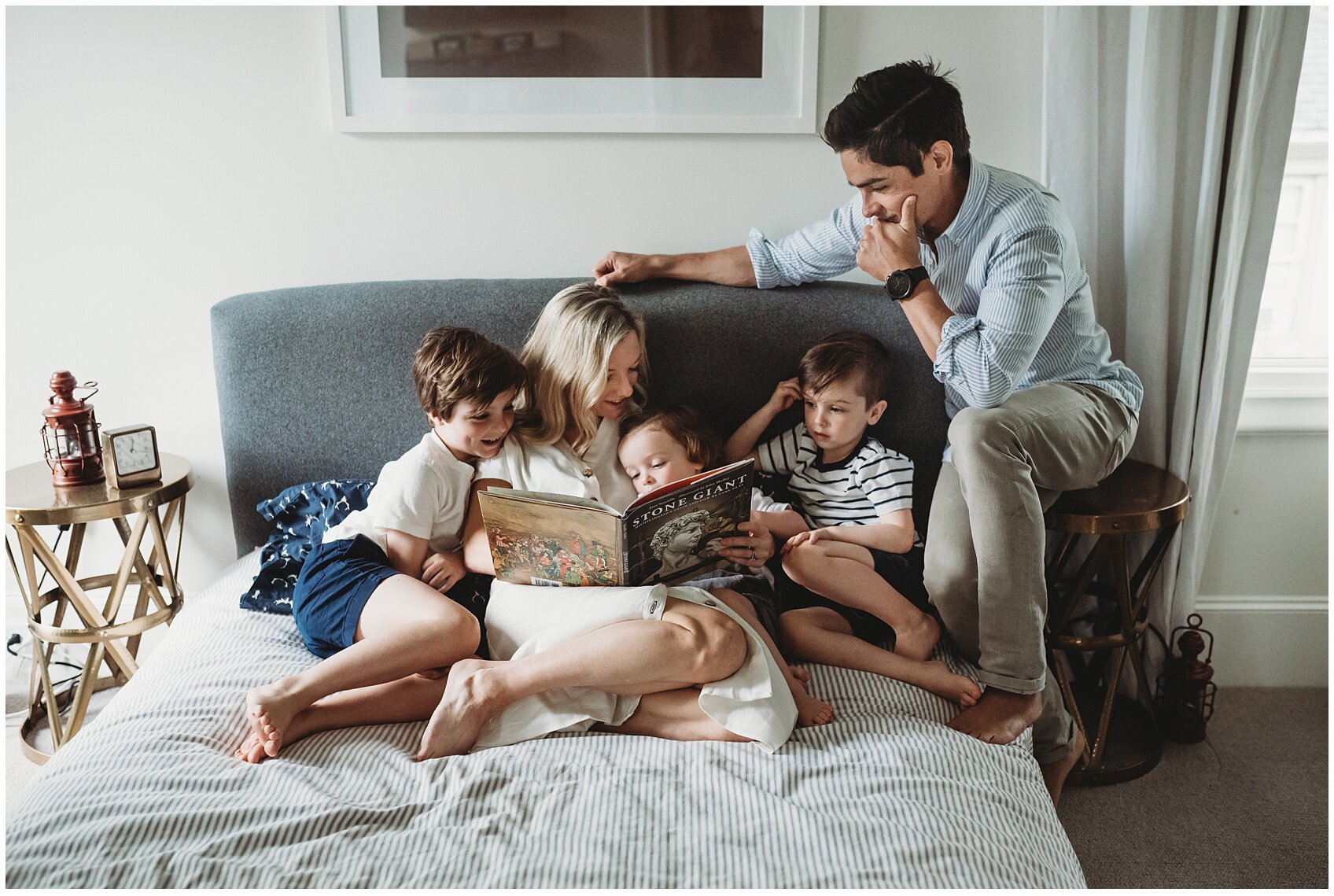 young family reading a book together on a bed