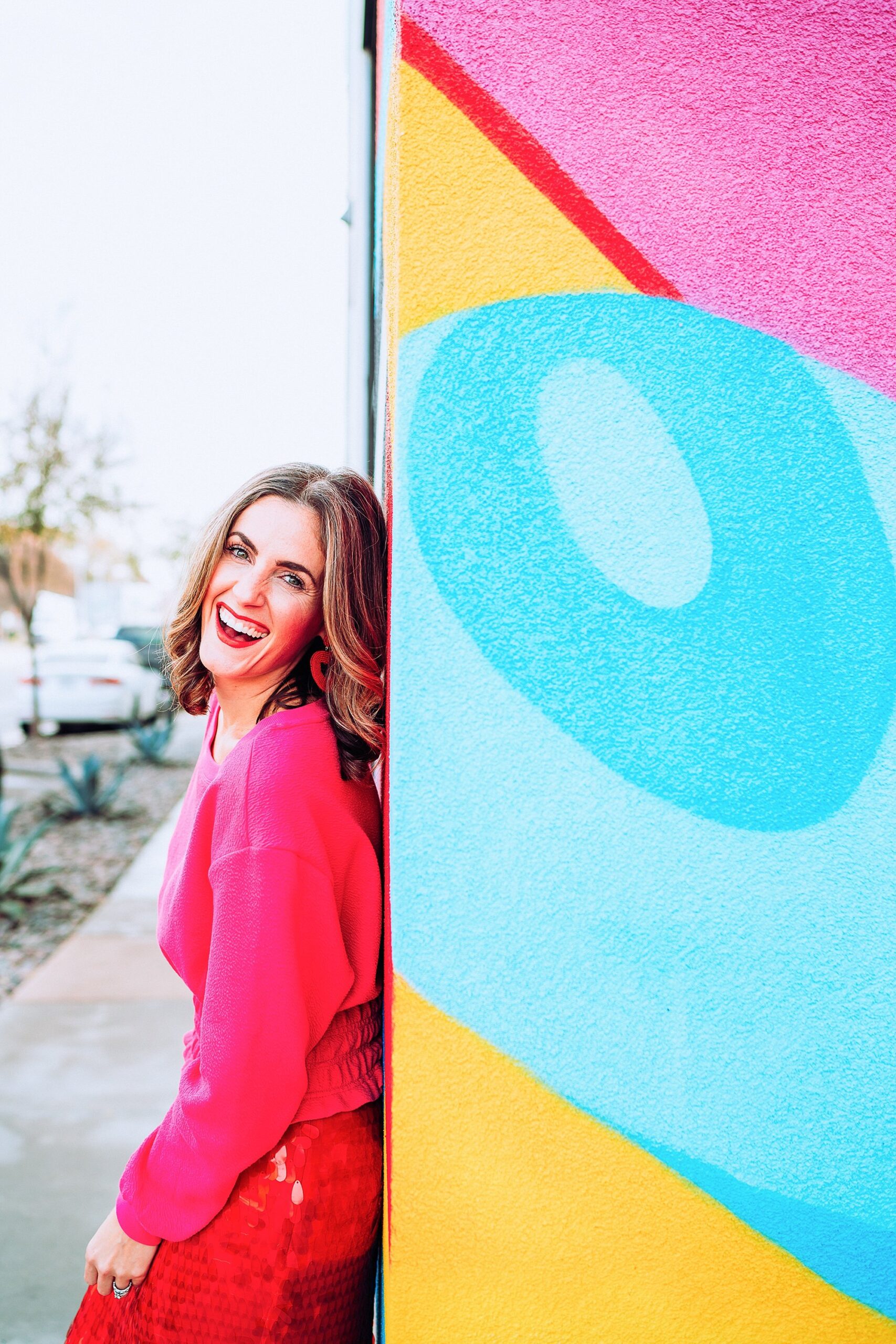woman in red standing in front of a colorful wall