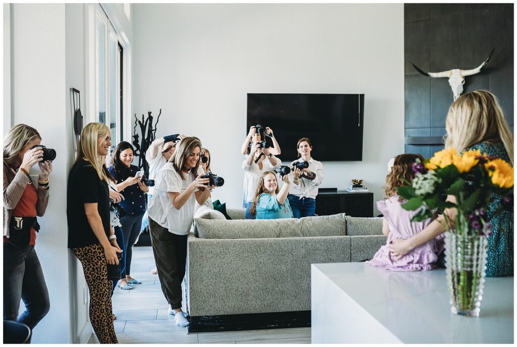 a group of photographers at an in person workshop photographing a family at home