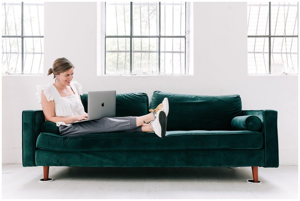 Female photographer entrepreneur working on a laptop in a green couch
