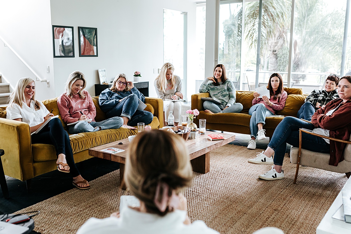 female photographers at an in-person mastermind sit in a living room to learn from each other