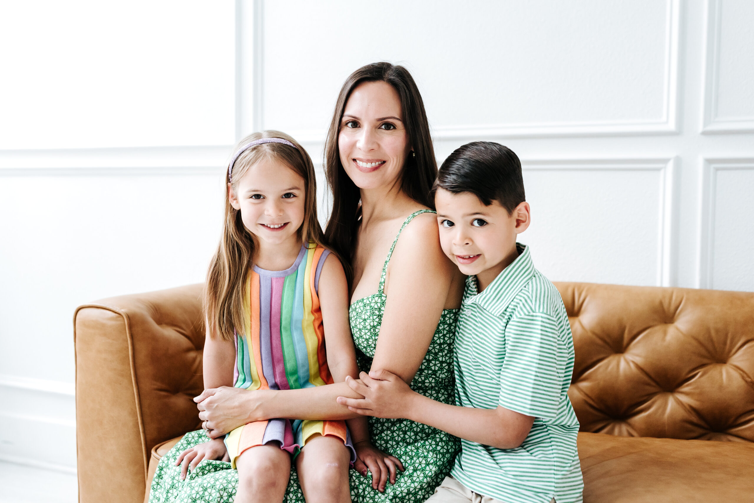 Mother with her two children smiling on a couch during photography mini sessions, showing why you should offer mini sessions as a photographer.