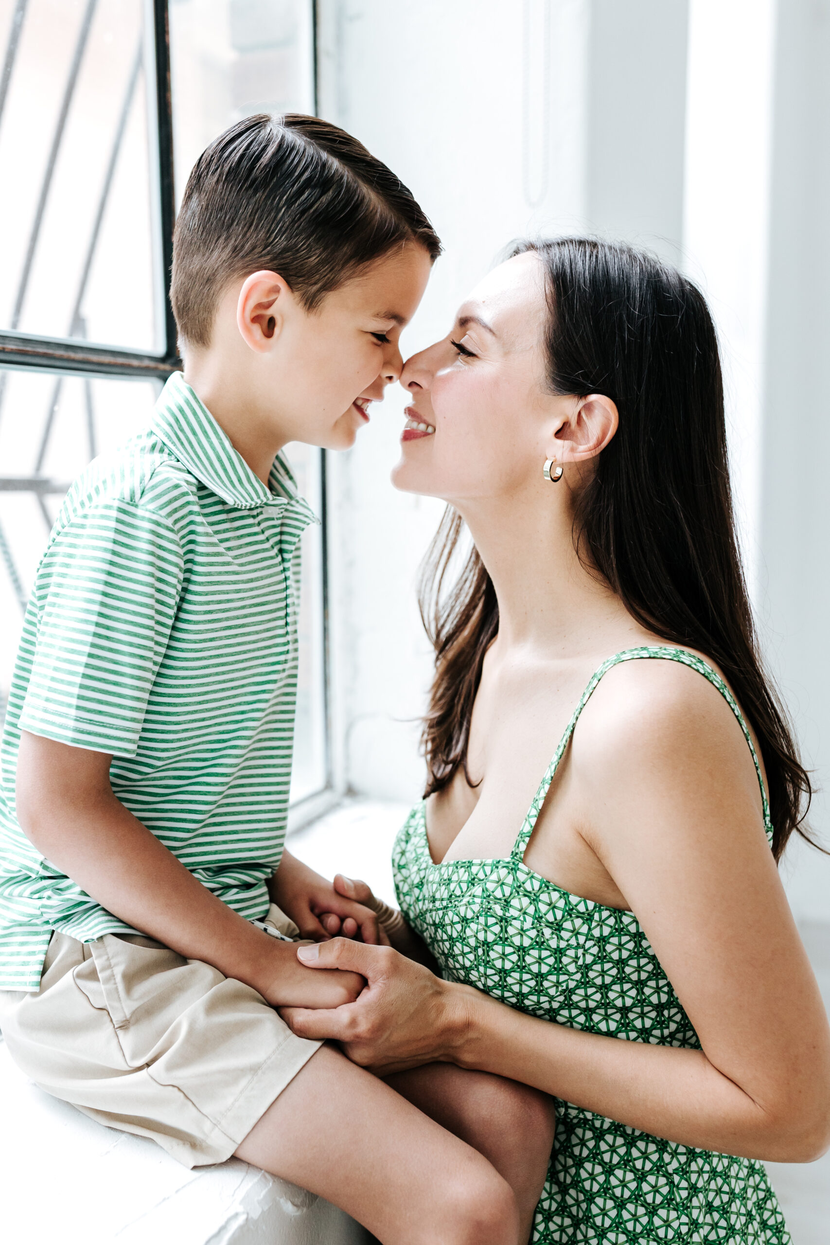 Sweet candid of mother and son nose to nose in natural light studio, an example of authentic moments captured in photography mini sessions.