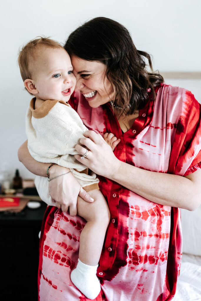 Mother cuddling her toddler and smiling, a heartfelt example of the real moments created during photography mini sessions.