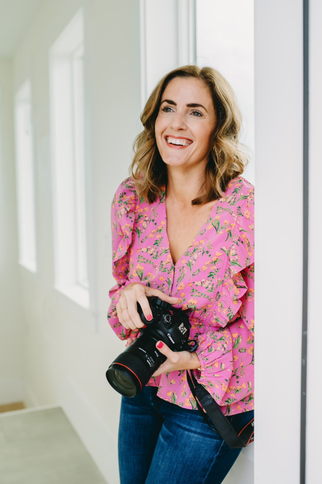 photographer and business coach, sabrina gebhardt, wearing a pink shirt and holding a camera at a mastermind retreat