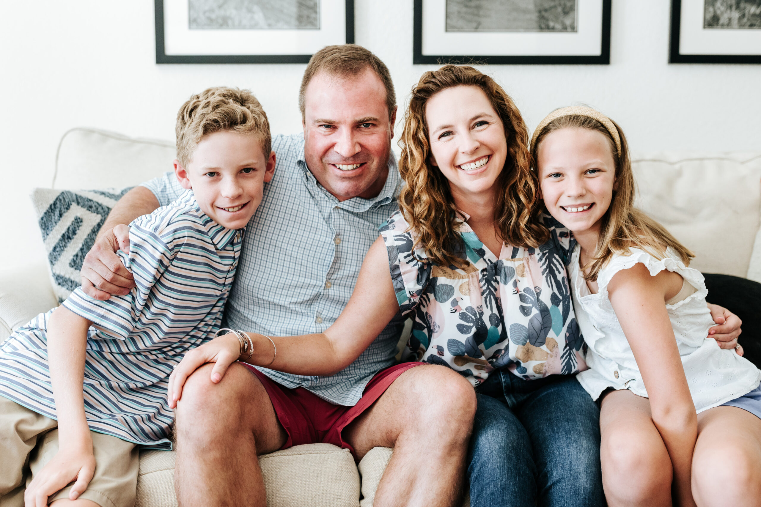 Happy family sitting closely on a couch, showing the connection that answers a common photographer FAQ about why parents should be in the frame.