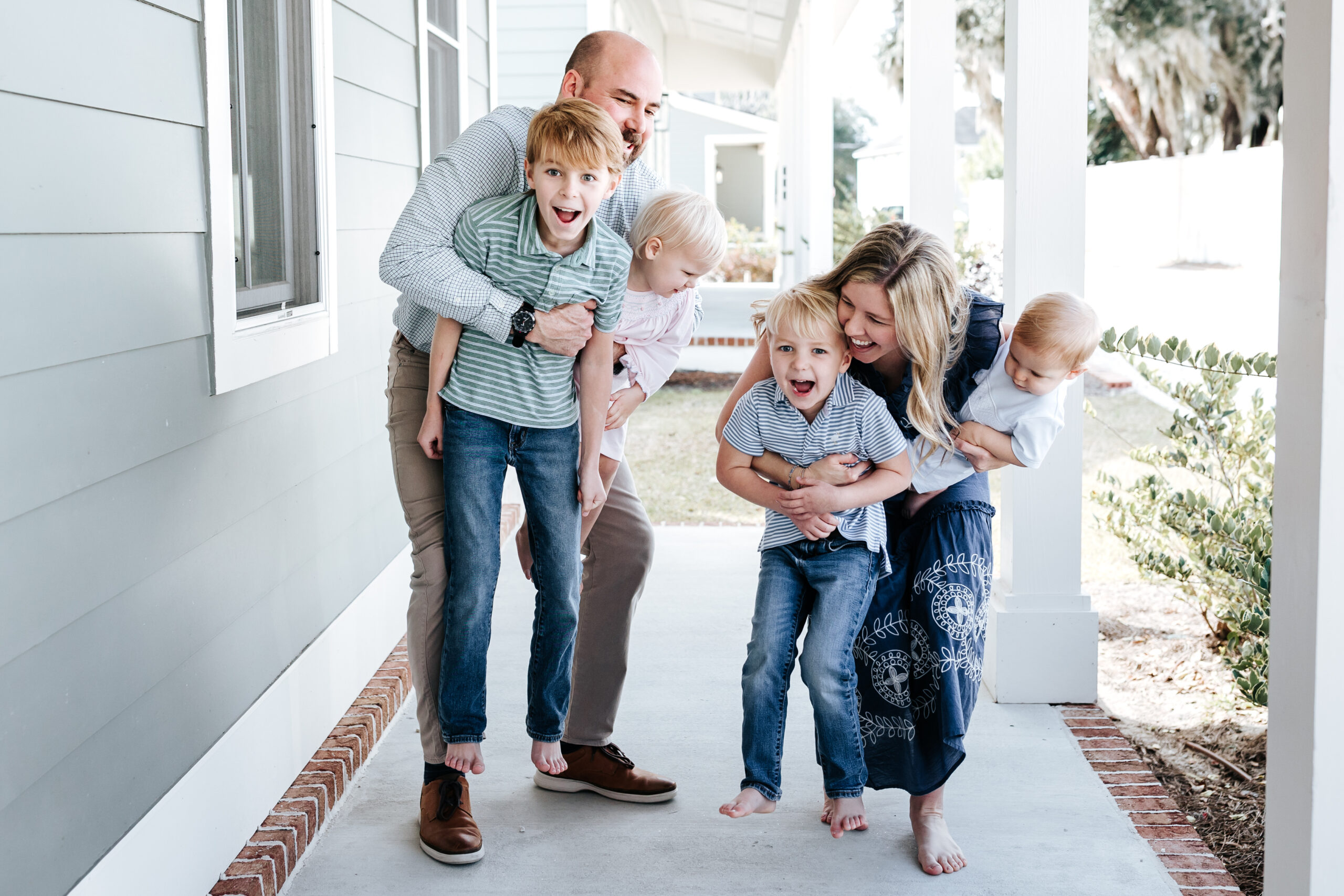 Playful front porch family session with young children, captured by a DFW Family Photographer during golden hour.