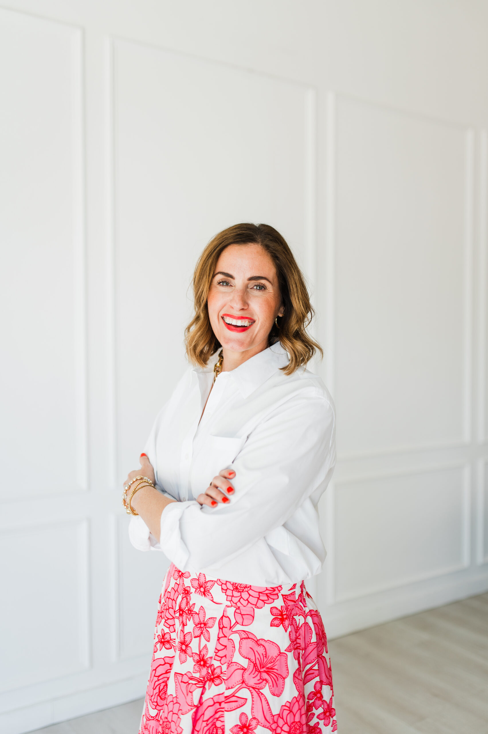 Confident businesswoman in a white shirt and floral skirt, smiling with arms crossed—highlighted in a Flodesk review.