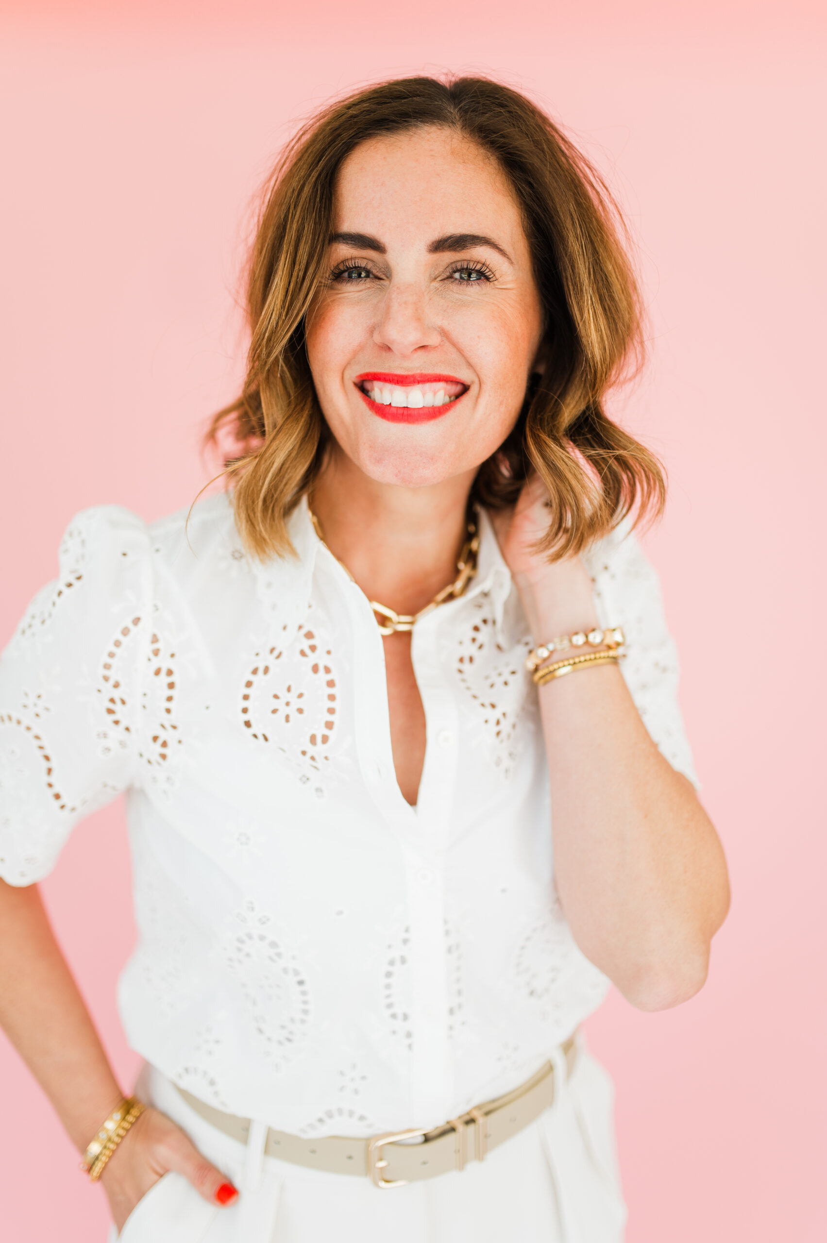 Portrait of a joyful business coach sharing photography business tips, smiling confidently in front of a pink backdrop.
