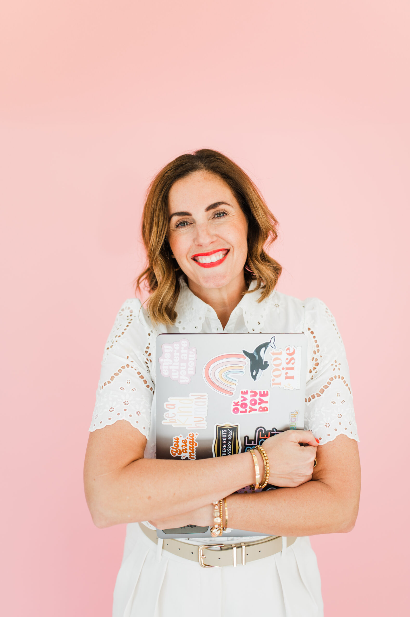 Email Marketing for Photographers: Build Relationships, Not Just a List 1 Woman in white eyelet blouse holding a sticker-covered laptop, representing fun and approachable email marketing for photographers.