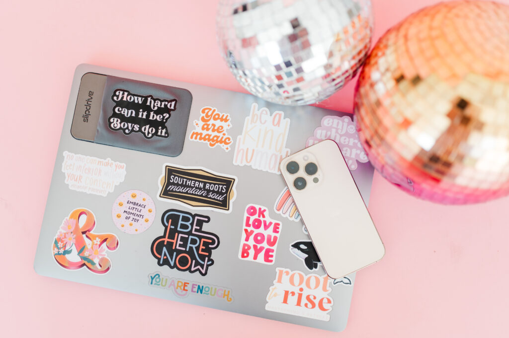 Email Marketing for Photographers: Build Relationships, Not Just a List 2 Laptop with colorful stickers and disco balls on a pink backdrop, symbolizing creative email marketing for photographers.