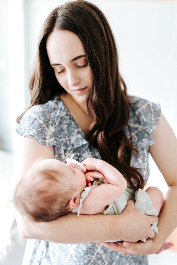 How to Create a Stress-Free Newborn Session at Home 7 Mother gazing softly at her baby while holding them close near a window with gentle natural light.