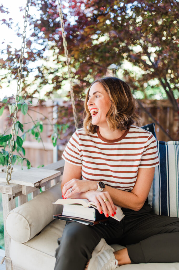 Photographer smiling on a porch swing while journaling, representing storytelling in photography through everyday inspiration.