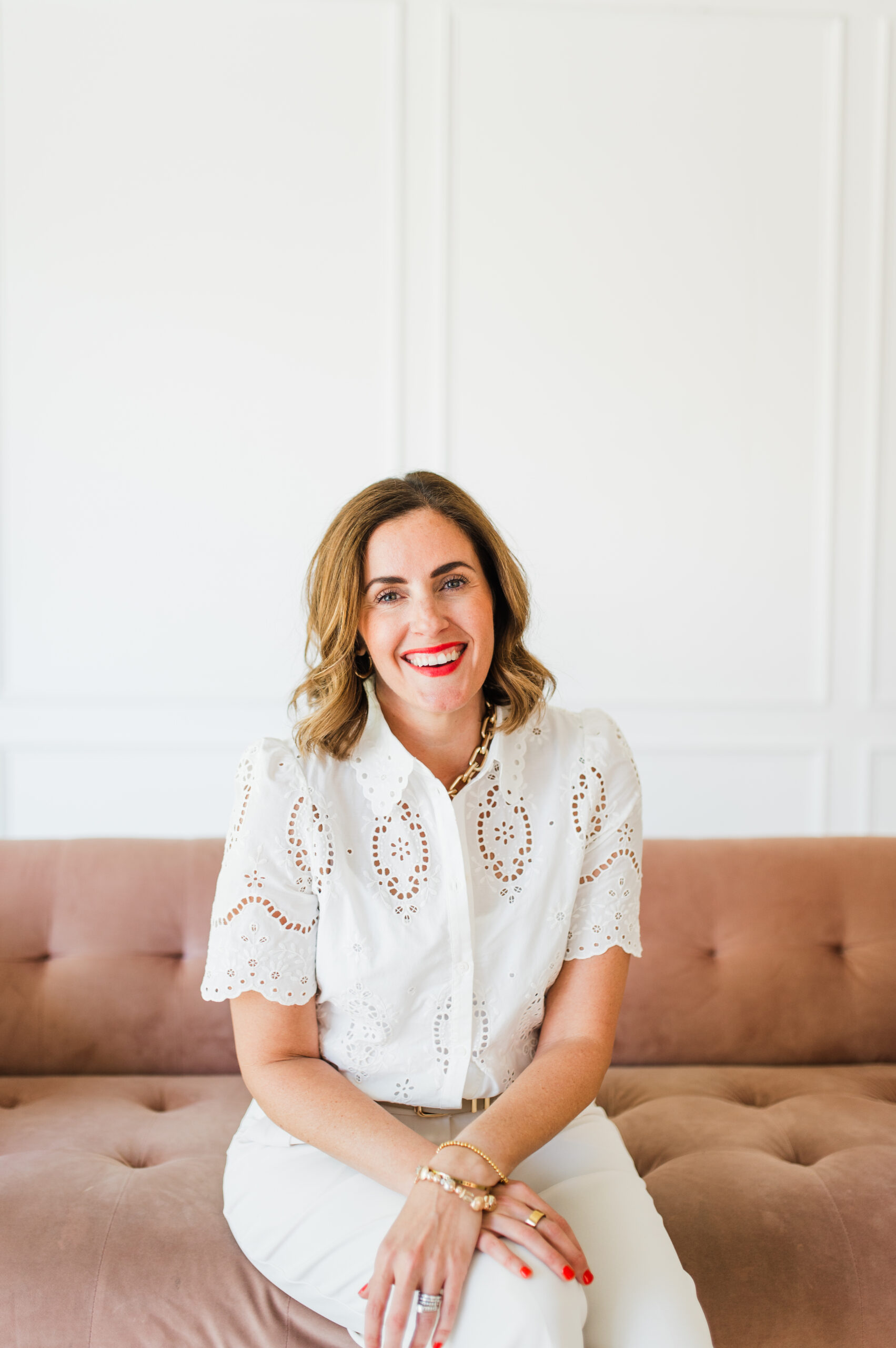 The Power of Storytelling in Photography (and Why It Matters for Your Business) 13 Photographer sitting on a pink couch, smiling confidently during a branding session that highlights storytelling in photography.