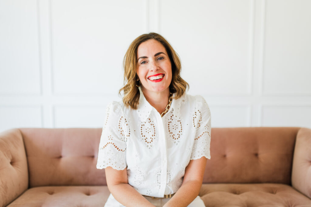 How to Find Photography Clients: The Ultimate Guide for Slow Seasons 1 Woman sitting on a blush pink sofa in bright studio light, reflecting on strategy and how to find photography clients with clarity and confidence.