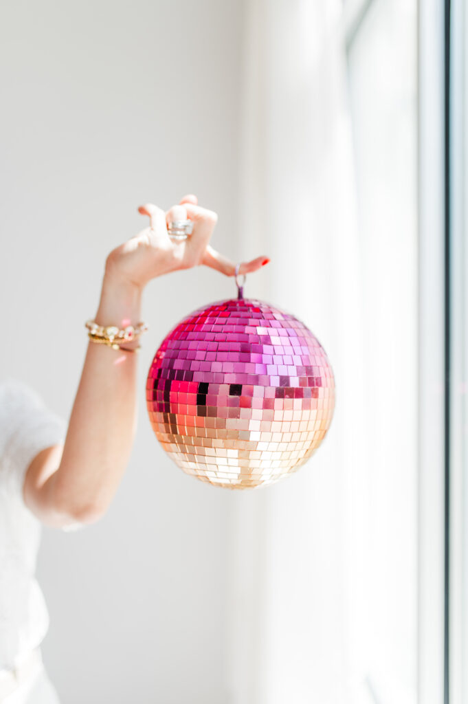 How to Find Photography Clients: The Ultimate Guide for Slow Seasons 2 Hand holding a pink and gold disco ball in bright natural light, representing creative energy and how to find photography clients with fun branding.