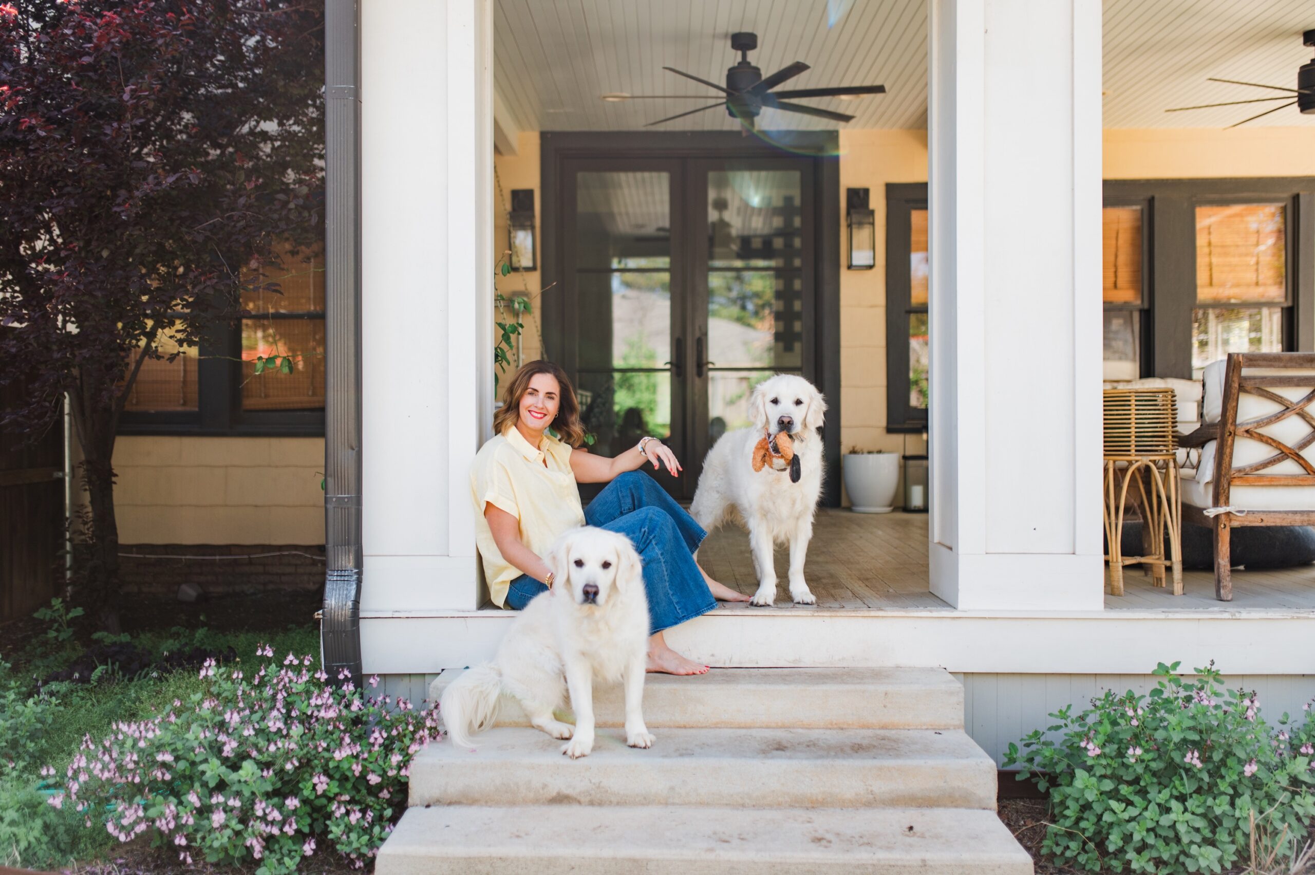 Woman sitting on a front porch with two white dogs, representing balance in business and avoiding common pricing mistakes photographers make.