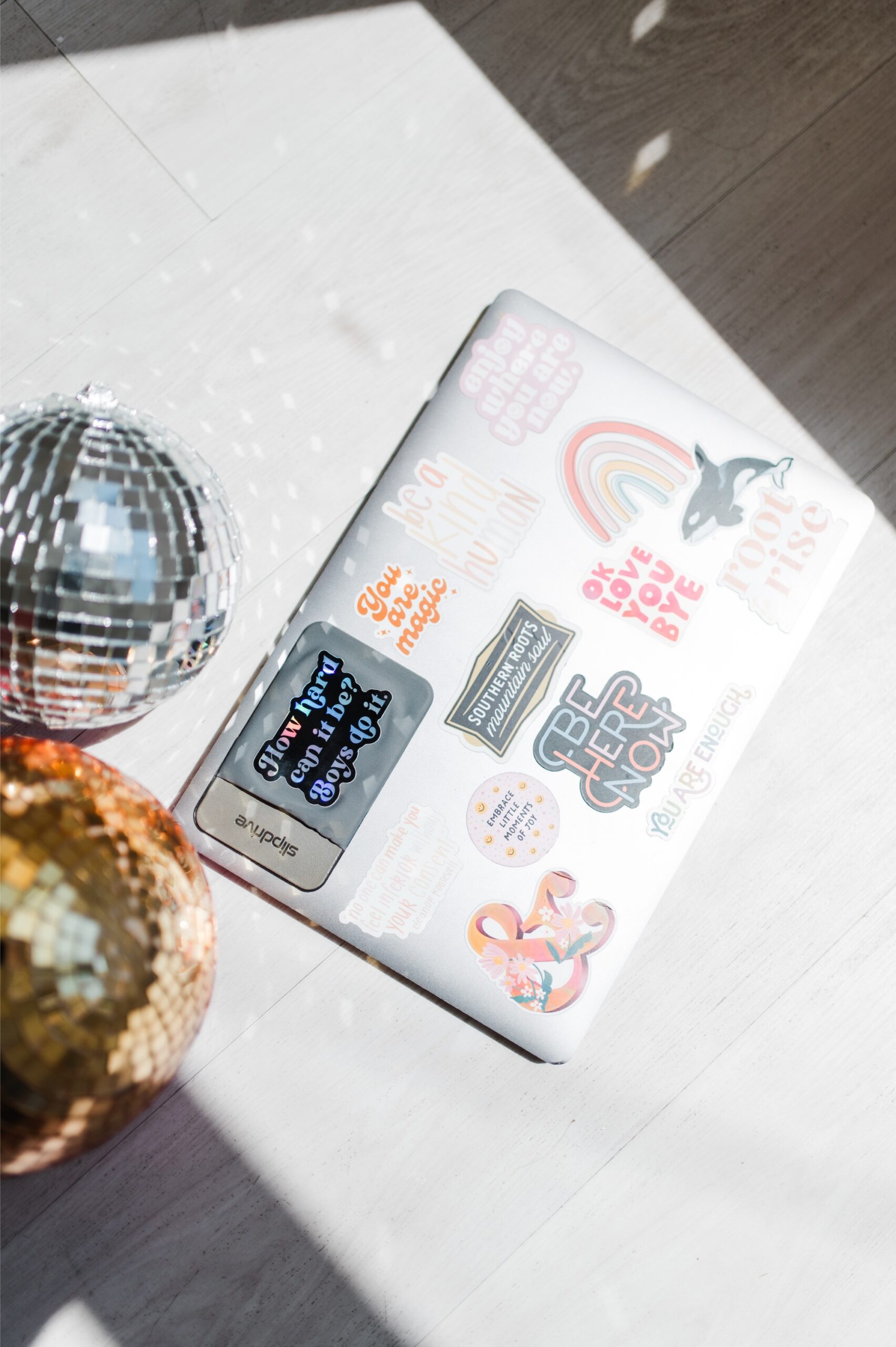 Laptop covered in creative stickers beside disco balls, representing the fun, modern approach to fixing pricing mistakes photographers make in their business.