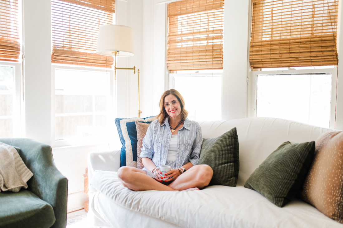 Relaxed lifestyle portrait of a photographer sitting on a couch with coffee in a light-filled living room