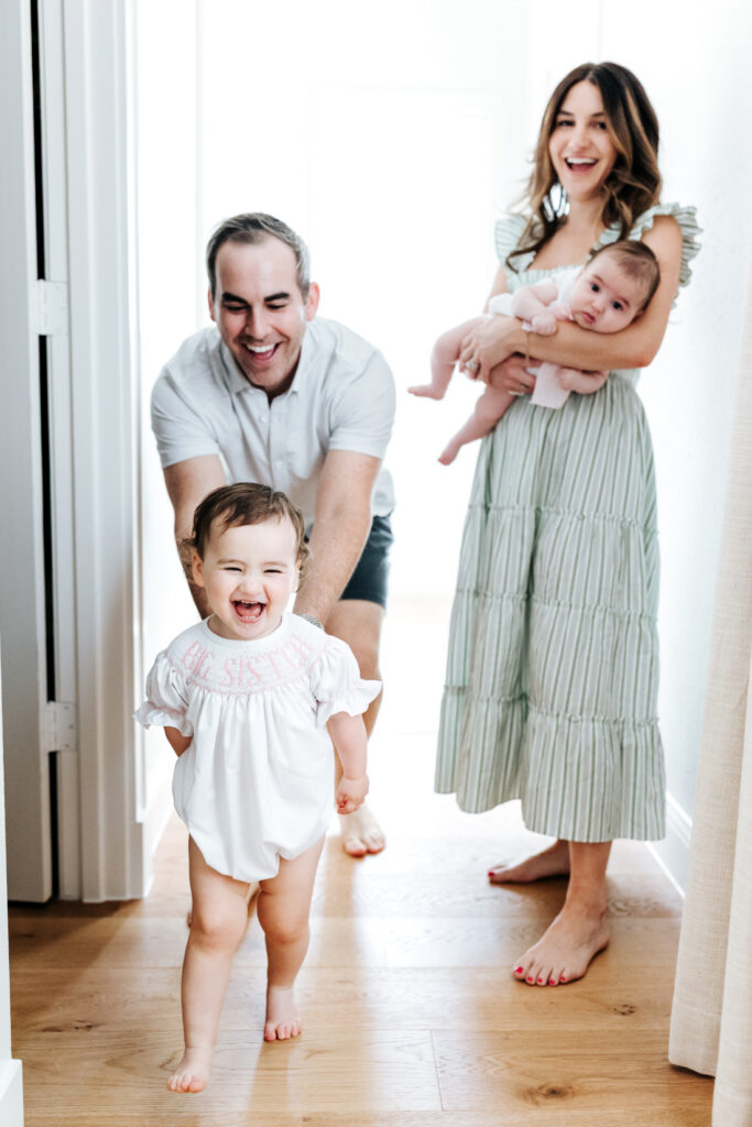 Toddler walking toward the camera while parents smile in the background, capturing natural movement in a lifestyle session
