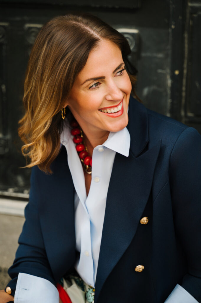 Smiling portrait of Sabrina Gebhardt wearing a navy blazer, white blouse, and statement necklace while teaching photographers about marketing without social media.