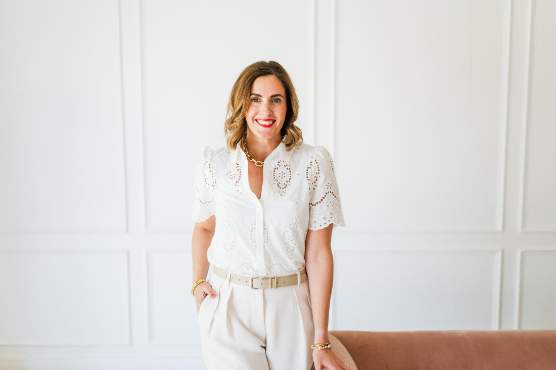 Sabrina Gebhardt smiling in a bright studio while wearing a white eyelet blouse and neutral pants.
