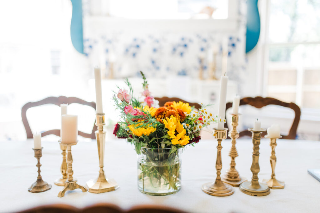 Colorful floral arrangement and gold candlesticks on a table, creating an inviting workspace for photography business planning.